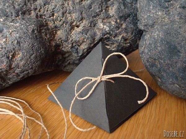 Krabička ve tvaru pyramidy z černého papíru a mašličkou s přírodního provázku.